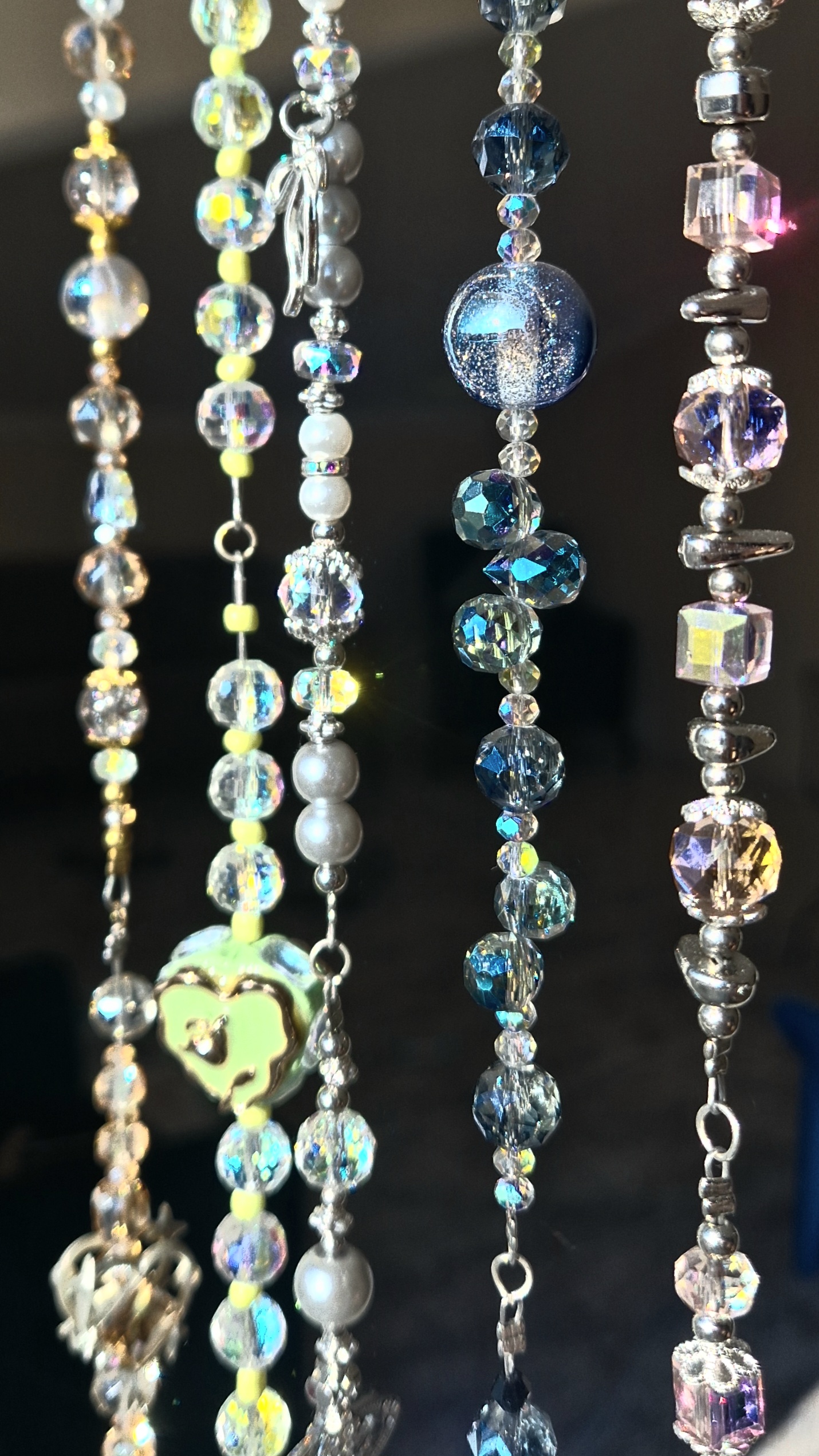 Close-up of handmade beaded strands with sparkling crystal and glass beads against a dark background